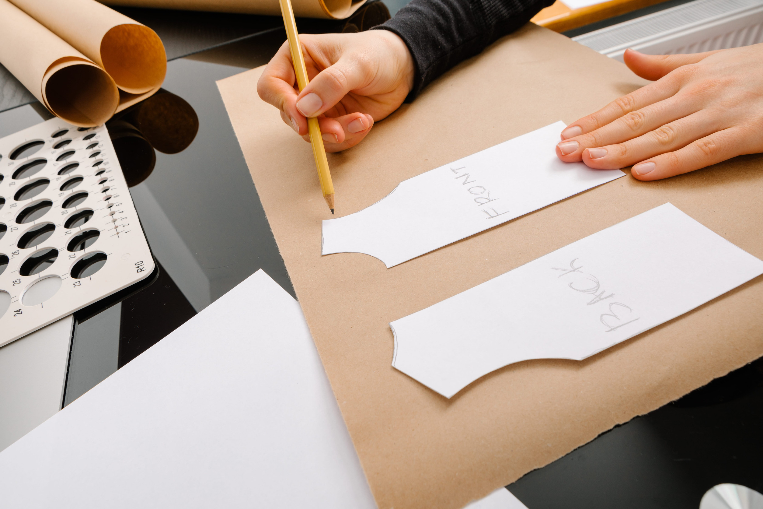 close up shot of a womans hands, drafting a pattern for a T shirt with both parts labeled back and front in Cape Town